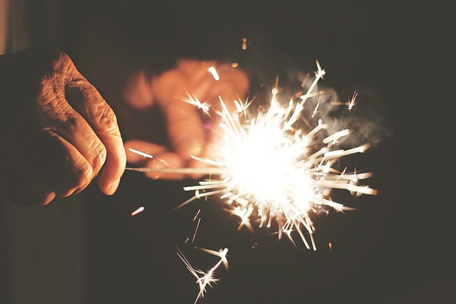 Man holding lit sparkler at night